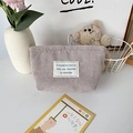 Close-up of a light gray corduroy cosmetic bag with a soft ribbed texture and woven label - Gray