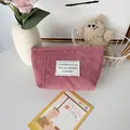 Detailed texture of pink corduroy makeup bag with minimalist white fabric label - Lotus Pink