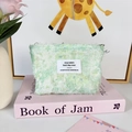 Detailed view of mint green plush chiffon floral makeup bag with woven brand label - Green Daisy