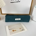 Close-up of dark green corduroy pencil case texture with minimalist woven label - Dark Green