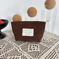 Detail of dark brown corduroy makeup bag showing ribbed texture and fabric label - Brown