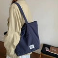 Minimalist deep blue nylon tote bag with shoulder strap and brand label shown on model - Navy Blue (beyoumerci Label)