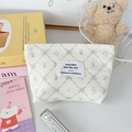 Dettaglio trousse in velluto a coste color panna con motivi a fiocco e zip - Bianco con fiocco a quadretti