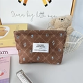 Dettaglio di una trousse in velluto marrone con motivi a fiocco e stampe floreali eleganti - Fiocco a Quadri Marroni
