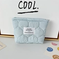 Close-up of light blue quilted cosmetic bag with white woven label and zipper detail - Quilted Gourd Blue