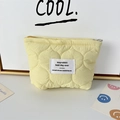 Detailed view of yellow quilted makeup bag with wave pattern and embroidered logo patch - Quilted Gourd Yellow