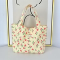 Close-up of floral quilted tote bag featuring strawberry patterns and top button closure - Yellow Floral