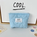 Close-up of light blue quilted makeup bag with zipper closure and white textile label - Quilted Flower Blue