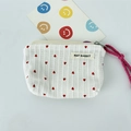 Close-up of striped makeup bag fabric with red heart patterns and brand label detail - Drawstring Pouch