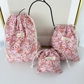 Detail of three floral drawstring storage bags in various sizes with white cotton cords - Large / Red Floral