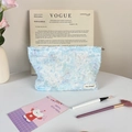 Close-up of light blue plush makeup bag featuring a soft fiber texture and brand label - Blue Daisy