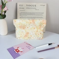 Elegante neceser de peluche con estampado floral y borla en un tocador con pinceles - Margarita Amarilla