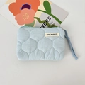Detailed close-up of a light blue quilted storage bag with a branded woven label and rope strap - Quilted Gourd Blue
