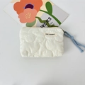 Close-up of cream quilted cosmetic bag with floral patterns and blue braided rope puller - Quilted Flower White