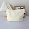 Détail de la trousse de maquillage en nylon crème avec étiquette logo et texture en tissu - Beige