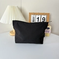Vue détaillée d'une trousse à maquillage en nylon noir avec fermeture éclair et étiquette - Noir