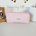 Close-up of pink waffle texture pencil case with brand label and round metal zipper pull - Light Pink
