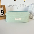 Detail of mint green waffle textured pouch with zipper closure and woven brand label - Green