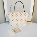 Detailed texture of seersucker makeup bag with red floral embroidery and brand label - Beige Floral Makeup Bag