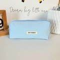 Macro shot of light blue waffle texture fabric and May Rabbit brand label on pencil case - Blue