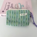 Detail der gewebten Mini-Kosmetiktasche mit lila Kordelgriff und bunten Streifenmustern - Grün