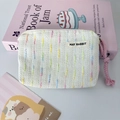 Close-up of small woven makeup bag with rainbow stripes and pink rope zipper pull - Off-white