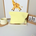 Detail of yellow waffle texture makeup bag with logo tag on a lifestyle desk setup - Yellow