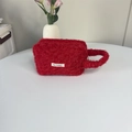 Detailweergave van de rode pluche make-uptas met zachte textuur en merklogo-label - Rood