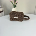 Detailopname van de donkerbruine pluche make-uptas met zachte May Rabbit label accenten - Bruin