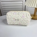 Detail van gewatteerde make-uptas met bloemenprint en geweven label van MAY RABBIT - Strik Hond