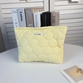 Gros plan d'une trousse de toilette matelassée jaune avec l'étiquette May Rabbit sur tissu - Gourde Matelassée Jaune