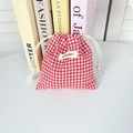 Detail of red and white checkered drawstring bag with white woven brand label - Red Plaid