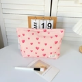 Detail van roze make-uptas met hartjespatroon van canvas met metalen rits en merklabel - Make-uptas