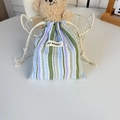 Détail de la pochette rayée bleue et violette avec étiquette May Rabbit dans un décor doux - Rayures Vert Violet