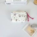 Detail of quilted mini pouch with rabbit patterns, zipper with pink cord, and woven label - Rabbit