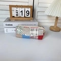 Detailed patchwork pencil case with floral patterns and logo tag on desk setup - Corduroy Puzzle Pattern