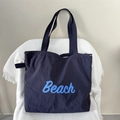 Detail of navy nylon tote bag showing Beach lettering print and drawstring closure - Beach Navy Blue