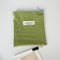 Detalle de neceser de viaje a cuadros verdes con cremallera azul y etiqueta blanca - Verde