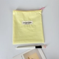 Vista macro de la bolsa de maquillaje a cuadros amarillos con cremallera rosa fina - Amarillo