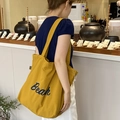 Dettaglio della borsa tote in tela giallo zenzero con scritte Beach blu in un contesto casual - Beach Giallo Zenzero