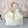 Detail der floralen Chiffon-Tasche mit Faltenstruktur und geflochtenen Seilgriffen - Cremeweiß