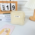 Close-up of minimalist beige checkered storage bag with zipper and branded label - Khaki Plaid