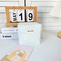 Detail van blauwe geruite katoenen zak met May Rabbit label op een bureau met decor - Lichtblauw Geruit
