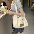 Detail of canvas tote bag with rabbit embroidery and steppy text on a shoulder strap - Little Rabbit