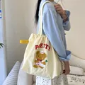 Beige canvas bucket bag with brown bear embroidery and PRETTY text on blue cardigan outfit - Pretty Bear (Beige)