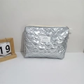 Detalle del patrón de corazón acolchado plateado y etiqueta tejida en el neceser metálico - Corazón de Plata