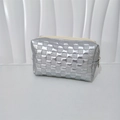 Detailed close-up of a silver quilted makeup bag with a metallic finish and zipper - Silver Small Grid