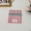 Macro detail of compact pink nylon coin purse with contrast green zipper and logo label - Pink