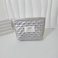 Close-up of quilted silver makeup bag with square pattern and minimalist woven label - Silver Small Grid