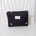 Close-up of black quilted makeup bag featuring white bow embroidery and metal zipper - Handbag Black